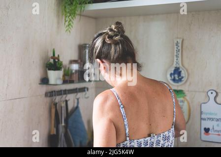 Junge Frau von hinten, die in der Küche Essen zubereitet. Stockfoto