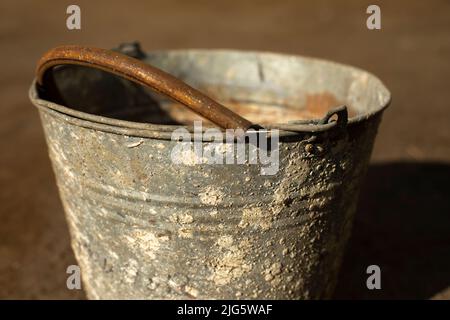 Alter Eimer aus Metall. Rostiger Eimer mit Flechten bedeckt. Altes Element. Junk auf der Straße. Stockfoto