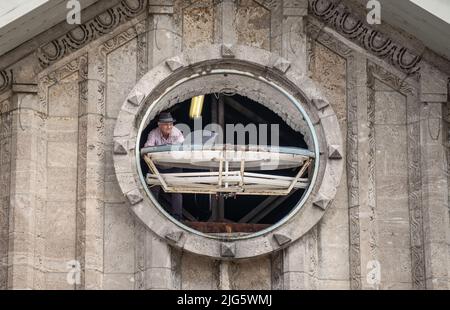 Darmstadt, Deutschland. 06.. Juli 2022. Hoch oben unter dem Dach des Darmstädter Hauptbahnhofs hält Uhrmacher Alexander Albrecht eine der frisch bemalten Hände über das Zifferblatt der Bahnhofsuhr. Der 61-jährige Frankfurter montiert, repariert und restauriert seit 1989 große Uhren aller Art. (Zu dpa-Korr 'Riesenuhren in luftiger Höhe - weitgereister Spezialist aus Hessen') Quelle: Frank Rumpenhorst/dpa/Alamy Live News Stockfoto