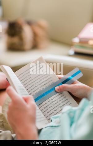 Legasthenie Kind Lesung mit Legasthenie Farbe Overlay in seinem Buch. Eine grüne Farbüberlagerung auf der Seite erleichtert das Lesen. Stockfoto