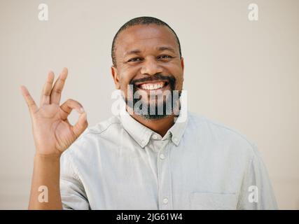 Alles wird in Ordnung sein. Aufnahme eines Mannes, der das OK-Schild zeigt, während er vor einem Studiohintergrund posiert. Stockfoto