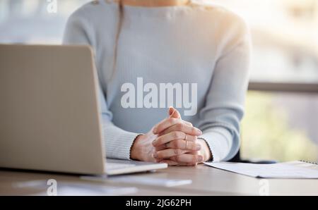 Verkaufen Sie mir Ihre Idee. Ausgeschnittene Aufnahme einer nicht erkennbaren Geschäftsfrau, die allein in ihrem Büro sitzt und ihre Hände zusammenhält. Stockfoto