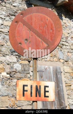 Rostiges Straßenschild ohne Parkplatz mit Einschusslöchern, die von Jägern als Ziel verwendet werden, mit der Aufschrift Fine, die das ENDE in der italienischen Sprache bedeutet Stockfoto