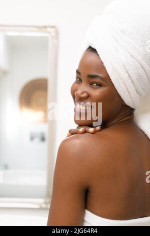 Nahaufnahme des Porträts einer lächelnden jungen afroamerikanischen Frau im Badezimmer zu Hause, Kopierraum Stockfoto