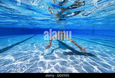 Detmold, Deutschland. 04.. Juli 2022. Ein Schwimmer schwimmt durch den Pool am Hiddesen Außenpool. Im Freibad in Detmold wird das Wasser nicht mehr mit Gas beheizt. Vor dem Hintergrund des russischen Angriffskrieges auf die Ukraine hatte die Stadt angekündigt, das Wasser in allen vier Außenpools nicht mehr zu heizen, um Gas für den Winter zu sparen. Quelle: Friso Gentsch/dpa/Alamy Live News Stockfoto