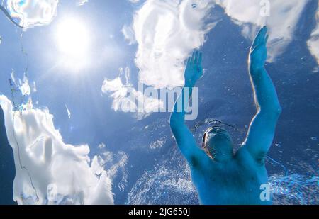 Detmold, Deutschland. 04.. Juli 2022. Ein Schwimmer schwimmt durch den Pool am Hiddesen Außenpool. Im Freibad in Detmold wird das Wasser nicht mehr mit Gas beheizt. Vor dem Hintergrund des russischen Angriffskrieges auf die Ukraine hatte die Stadt angekündigt, das Wasser in allen vier Außenpools nicht mehr zu heizen, um Gas für den Winter zu sparen. (Um dpa-Korr 'Einfrieren gegen Putin? Der Außenpool in Detmold heizt nicht mehr Wasser') Quelle: Friso Gentsch/dpa/Alamy Live News Stockfoto