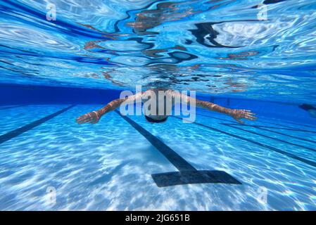 Detmold, Deutschland. 04.. Juli 2022. Ein Schwimmer schwimmt durch den Pool am Hiddesen Außenpool. Im Freibad in Detmold wird das Wasser nicht mehr mit Gas beheizt. Vor dem Hintergrund des russischen Angriffskrieges auf die Ukraine hatte die Stadt angekündigt, das Wasser in allen vier Außenpools nicht mehr zu heizen, um Gas für den Winter zu sparen. (Um dpa-Korr 'Einfrieren gegen Putin? Der Außenpool in Detmold heizt nicht mehr Wasser') Quelle: Friso Gentsch/dpa/Alamy Live News Stockfoto