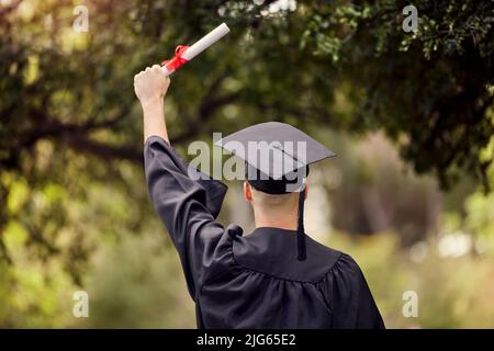 Von hier an kann es nur noch besser werden. Rückansicht eines jungen Mannes, der am Tag der Abschlussfeier jubelt. Stockfoto