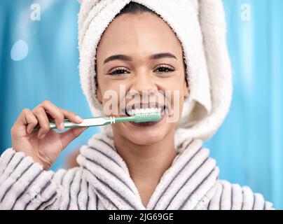 Halten Sie diese perlenden Weißen so weiß wie Perlen. Ein Porträt einer attraktiven jungen Frau, die sich im Badezimmer zu Hause die Zähne putzt. Stockfoto