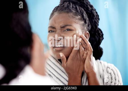 Ich kann mir im Moment keinen Ausbruch leisten. Eine kurze Aufnahme einer attraktiven jungen Frau, die zu Hause einen Pickel im Badezimmer knallte. Stockfoto
