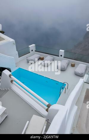 Atemberaubende Villa mit Swimmingpool im typischen weißgetünchten kykladischen Stil mit Blick auf die neblige Ägäis in Imerovigli Santorini Stockfoto