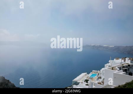 Atemberaubende Villa mit Swimmingpool im typischen weißgetünchten kykladischen Stil mit Blick auf die neblige Ägäis in Imerovigli Santorini Stockfoto