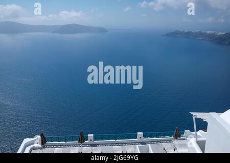 Eine wunderschöne, weiß getünchte Terrasse mit Sonnenliegen und einem atemberaubenden Blick über die Ägäis in Santorini Griechenland Stockfoto