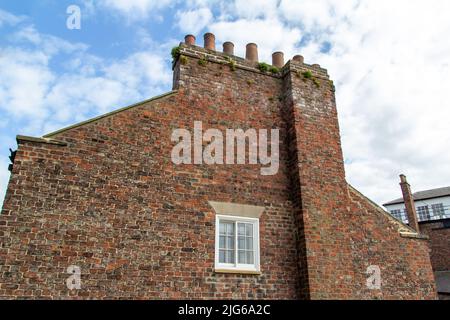 Nahaufnahme der alten europäischen Backstein- und Steinarchitektur mit Blick auf Kamine und ein kleines Fenster Stockfoto