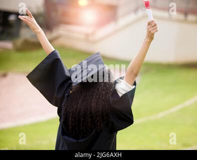 Ich muss noch weiter steigen. Rückansicht einer jungen Frau, die am Tag der Abschlussfeier jubelt. Stockfoto