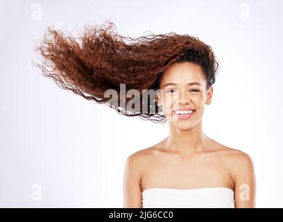 So glänzend, dass man es kaum glauben kann. Porträt einer jungen Frau mit fließenden Locken vor weißem Hintergrund. Stockfoto