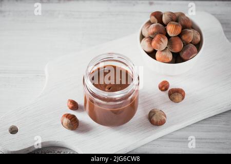 Hausgemachte Schokolade Haselnuss Milch auf einem weißen Holzhintergrund verteilt Stockfoto