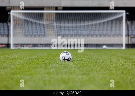 Football ball on fresh green grass pitch. Soccer ball at big stadium Stockfoto