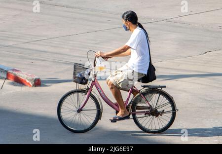 SAMUT PRAKAN, THAILAND, APR 15 2022, Eine Frau fährt auf einem Fahrrad auf der Stadtstraße. Stockfoto