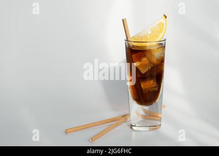 Glas Cola mit Eis, Zitrone und Stroh auf weißem Hintergrund Stockfoto
