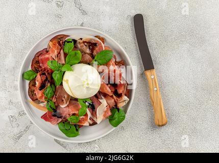 Italienischer Prosciutto mit Burrata-Käse, frischem Basilikum, Tomaten und Balsamico-Essig. Flatlay. Stockfoto