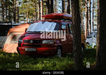 Leningrad, Russland - Juni 2022. Camping für Autos in der Natur im Nadelwald. Stilvoller roter Volkswagen Transporter mit Box auf Dach - House on Stockfoto