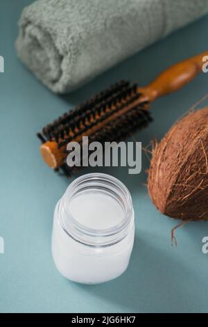 Kokosöl in einer Flasche mit Kokosnüssen, Handtuch und Haarbürste Stockfoto