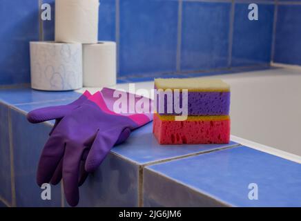 Gummihandschuhe und Schwämme im Badezimmer. Nahaufnahme. Set aus farbenfrohem Accessoire für die Hausreinigung. Sauberes Haus. Vorderansicht. Stockfoto