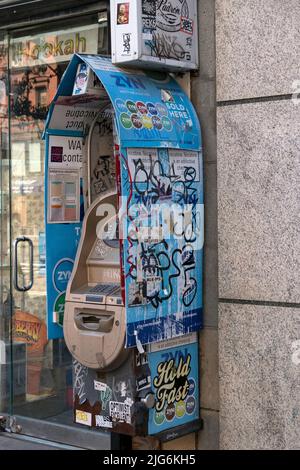 Ein Geldautomat auf der Second Avenue im East Village mit Aufklebern, Graffiti, Schildern und Hinweisen. In Manhattan, New York City. Stockfoto