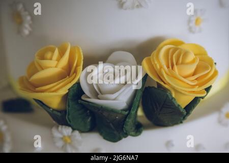Eine Nahaufnahme von gelben und weißen Rosen auf einem Hochzeitstorte aus Sahnehäubchen als Kuchendekoration Stockfoto