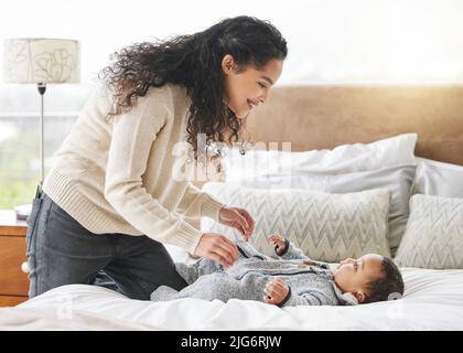 Wir bringen dich in eine frische Windel. Aufnahme eines entzückenden Jungen und seiner Mutter, die sich während des Windelwechsels zu Hause anklebten. Stockfoto