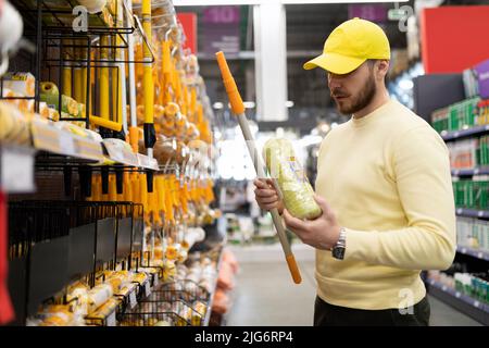 Ein Mann in einem Baumarkt wählt eine Walze für Malarbeiten Stockfoto