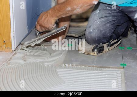 Um Klebstoff auf Fliesen zu kleben, zuerst feuchten Mörtel verteilen Stockfoto