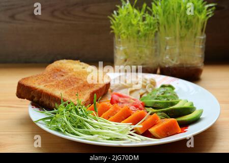 Köstliches frisches Wasser Spinat Microgreens und Avocado mit gedämpftem Kürbissalat zum Frühstück Stockfoto