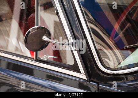 Seitlicher Rückspiegel im runden verchromten Rahmen. Schwarzes Oldtimer-Fragment, Nahaufnahme mit selektivem Weichfokus Stockfoto