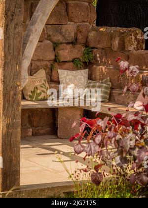 Holzgartensitz mit Streuspitzen, Teil eines Showgartens in der Hampton Court Palace Gartenschau in London. Stockfoto