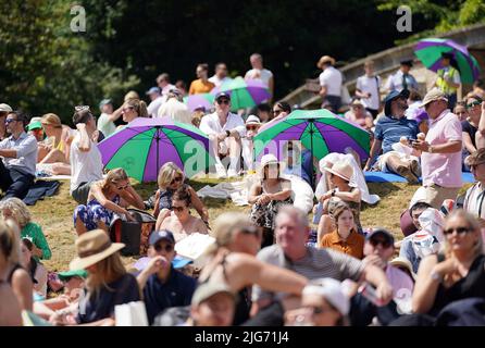 Am 12. Tag der Wimbledon Championships 2022 im All England Lawn Tennis and Croquet Club, Wimbledon, schützen sich die Zuschauer vor der Sonne. Bilddatum: Freitag, 8. Juli 2022. Stockfoto