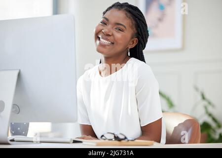 Ein Lächeln kann jeden Tag erhellen. Aufnahme einer jungen afrikanischen Geschäftsfrau, die an ihrem Computer arbeitet. Stockfoto