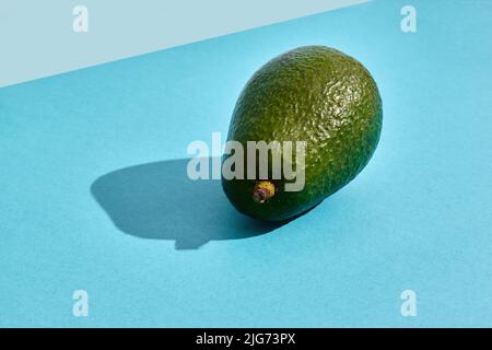 Nahaufnahme von hochwertigem Bild der ganzen Avocado, Fruchtkomposition auf blauem Pastell Stockfoto