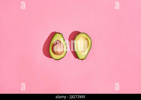 Zwei halbe Avocado-Früchte auf rosa Hintergrund Stockfoto