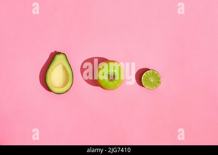 Halb Avocado Früchte Apfel auf rosa Hintergrund Stockfoto