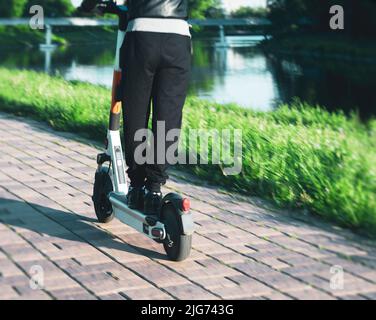 Junger Mann auf einem elektrischen Tretroller an der Stadtpromenade Stockfoto