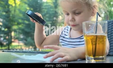 Kleines Mädchen schaut vorsichtig in die Linse auf das Salz. Nahaufnahme des blonden Mädchens studiert Salzkristalle, während sie durch Vergrößerungen betrachtet wird Stockfoto