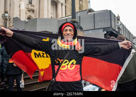 Melbourne, Australien. 8.. Juli 2022. Ein Mann posiert mit der indigenen Flagge beim NAIDOC Week march vor dem parlamentsgebäude. Quelle: Jay Kogler/Alamy Live News Stockfoto