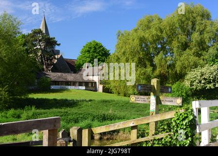 South Downs Way-Schilder neben dem Cuckmere River und der St. Andrew's Church in Alfriston, East Sussex. Stockfoto