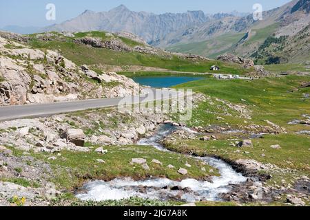 Blick auf das Hochplateau mit Lac des Eissaupres neben der Bergstraße von der Route de Col de la Bonette e Restefond, im Vordergrund schnell fließend Stockfoto