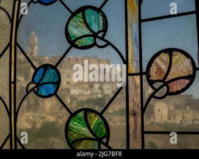 Panoramablick auf das alte Sassi-Viertel von Matera durch ein Buntglasfenster in einer Kirche im Tal Stockfoto