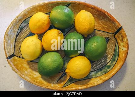 Zitrusfrüchte sitzen in einer gemusterten ovalen Holzschale. Stockfoto