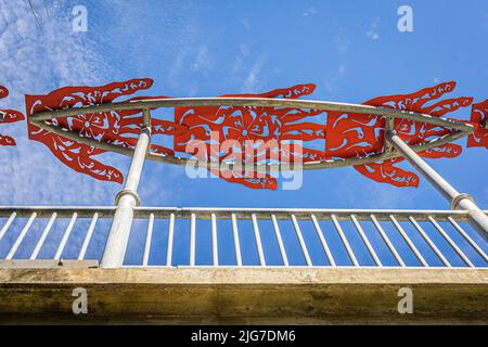 Rote Metallhandausschnitte über einer Brücke auf dem San Antonio River Walk. Stockfoto