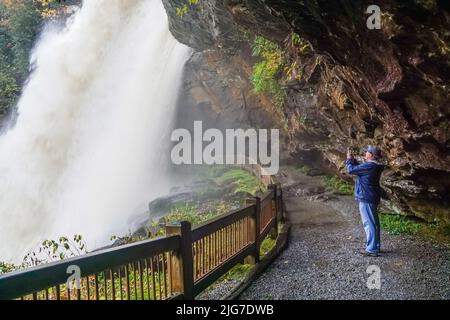 Der männliche Wanderer steht hinter dem Wasserfall Dry Falls in North Carolina auf der Spur Stockfoto